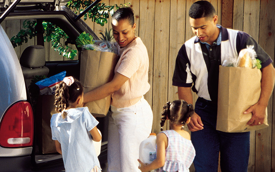 Photo: Young minority family unloading groceries from car